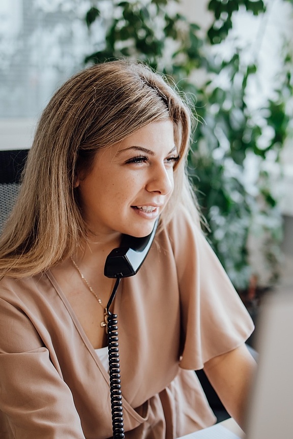 Blonde Frau am Schreibtisch sitzend und telefonierend