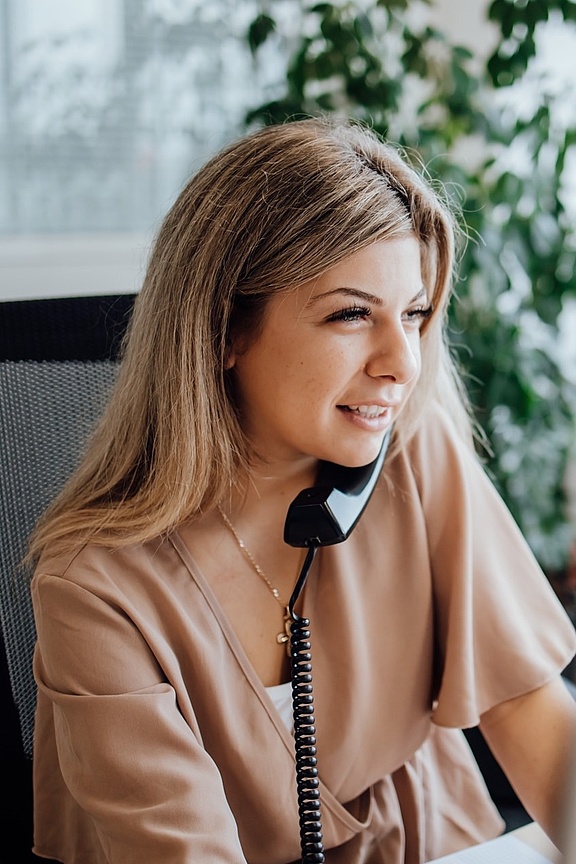 Blonde Frau am Schreibtisch sitzend und telefonierend