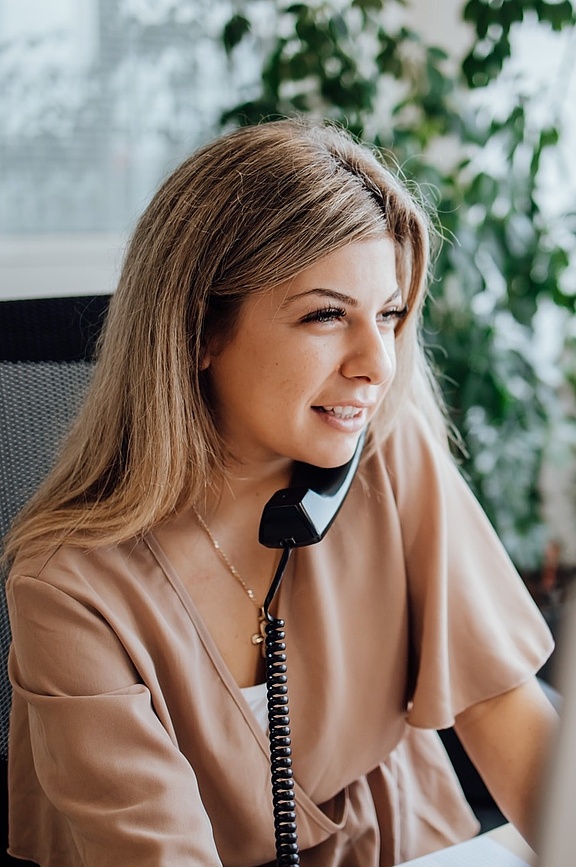 Blonde Frau am Schreibtisch sitzend und telefonierend