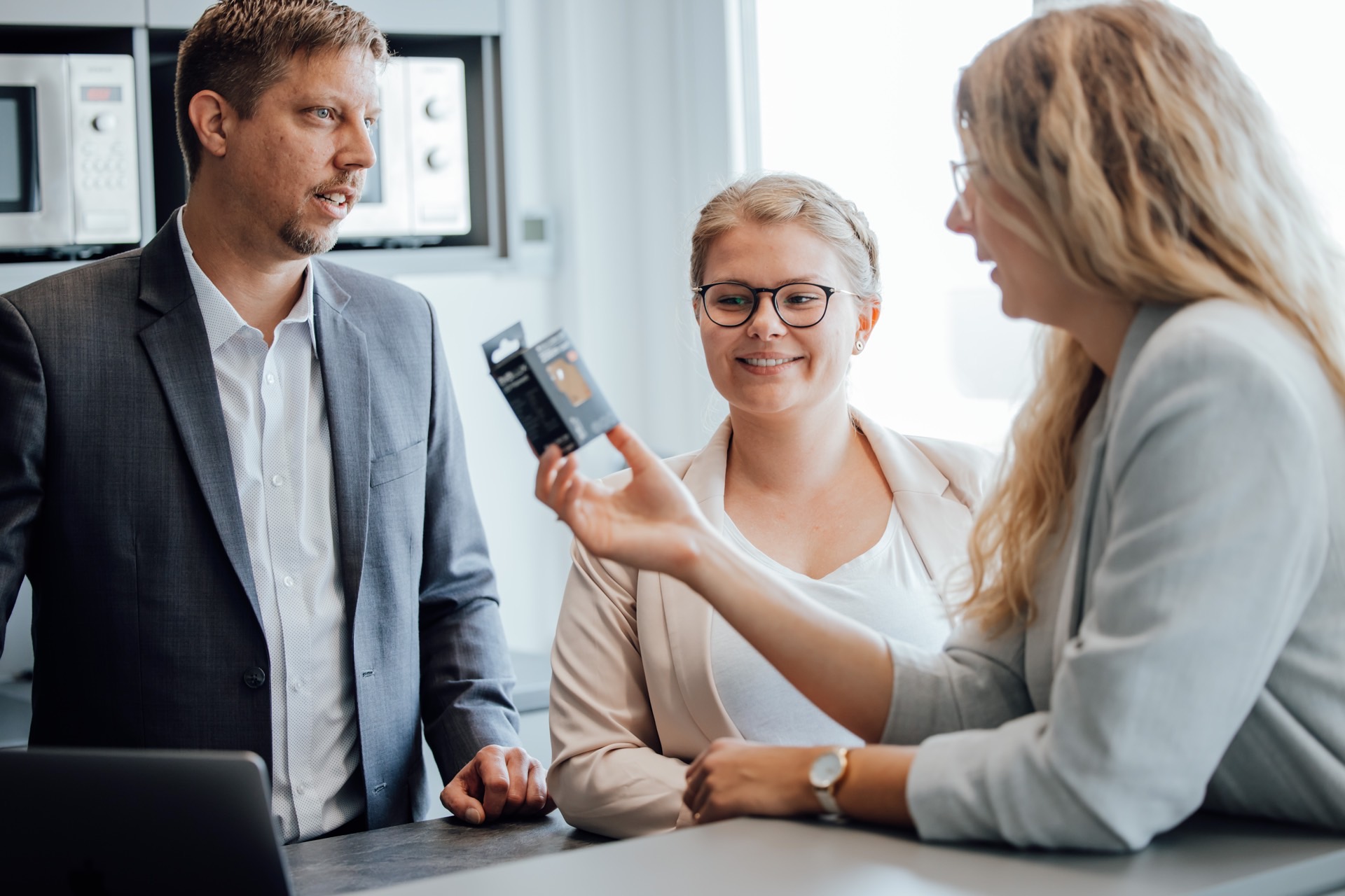 Zwei Frauen und ein Mann im Gespräch über ein Produkt 