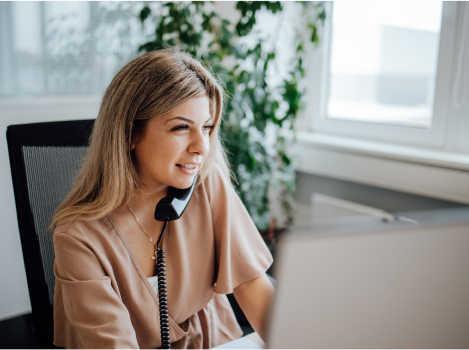 Blonde Frau am Schreibtisch sitzend und telefonierend